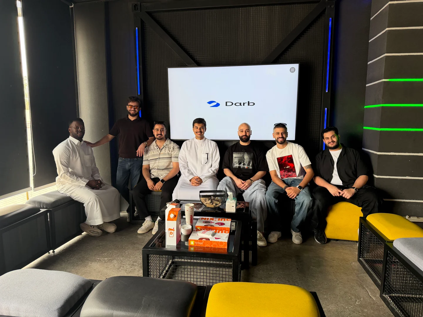 The Darb team together in front of a screen displaying the Darb logo.