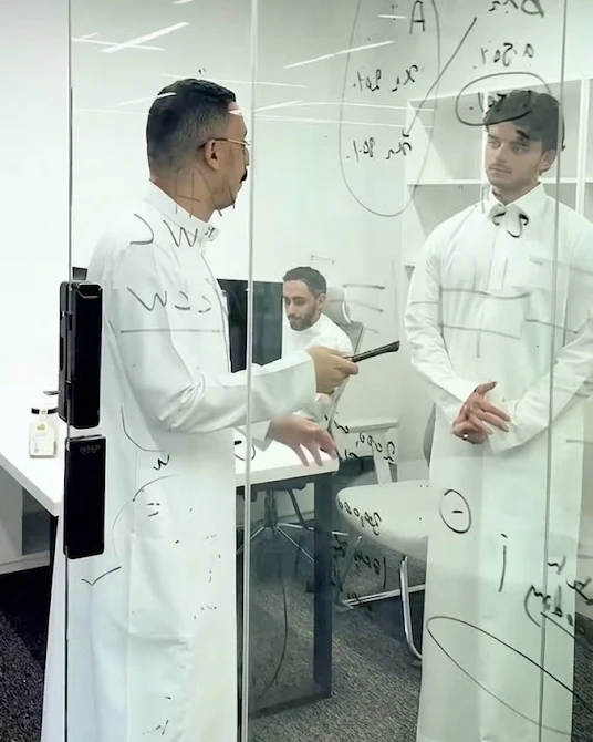 Team members discussing ideas on a glass board in an office.
